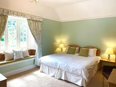 a bedroom with a bed and two windows at Polraen Country House Hotel in Looe