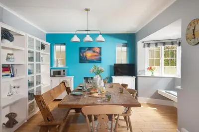 a dining room with a wooden table and blue walls at Mermaid Cottage, Carbis Bay in Carbis Bay