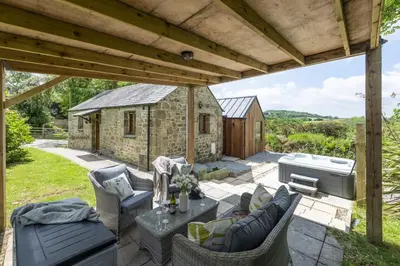 a patio with a table and chairs and a building at Relaxing getaway with a Hot Tub, Wi-Fi in Bodmin