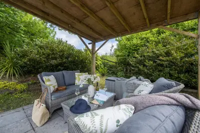 a patio with couches and chairs under a gazebo at Relaxing getaway with a Hot Tub, Wi-Fi in Bodmin