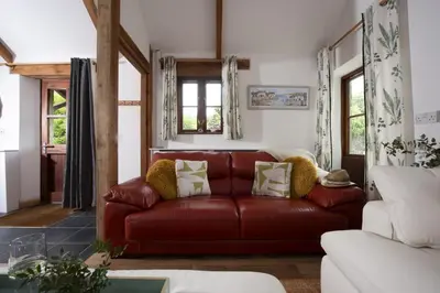 a living room with a red leather couch at Relaxing getaway with a Hot Tub, Wi-Fi in Bodmin