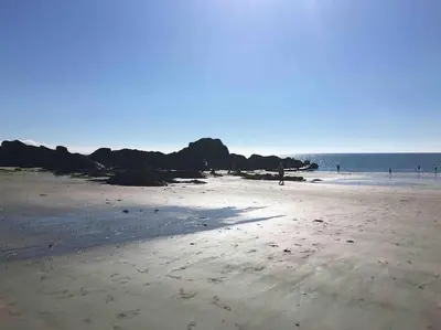 a beach with people walking on the sand and the ocean at Contemporary 3-Bedroom Home with Stunning Views in Looe
