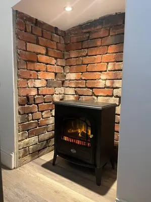 a brick wall with a fireplace in a room at Contemporary 3-Bedroom Home with Stunning Views in Looe