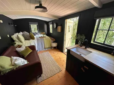 a bedroom with a bed and a couch and a sink at Cornwall Woodland Shepherd's Hut - Dennis Hut in Bodmin