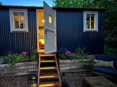 a tiny house with a door and stairs to it at Cornwall Woodland Shepherd's Hut - Dennis Hut in Bodmin