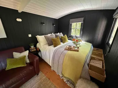 a bedroom with a large bed and a couch at Cornwall Woodland Shepherd's Hut - Dennis Hut in Bodmin
