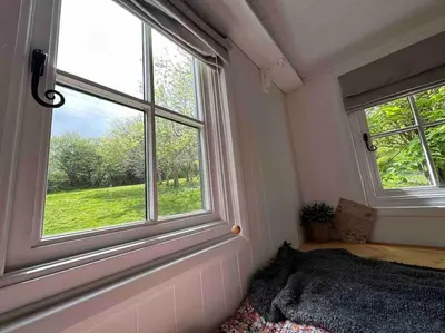 a bedroom with two windows and a bed in it at Cornwall Woodland Shepherd's Hut with Hot Tub - Deirdres Hut in Bodmin