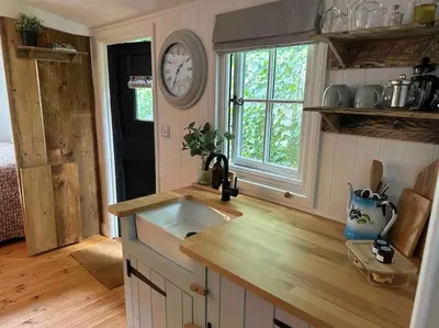 a kitchen with a sink and a clock on the wall at Cornwall Woodland Shepherd's Hut with Hot Tub - Deirdres Hut in Bodmin