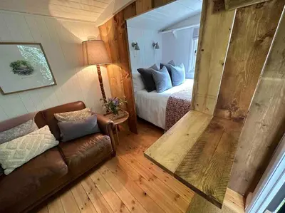 a room with a bed and a couch and a mirror at Cornwall Woodland Shepherd's Hut with Hot Tub - Deirdres Hut in Bodmin