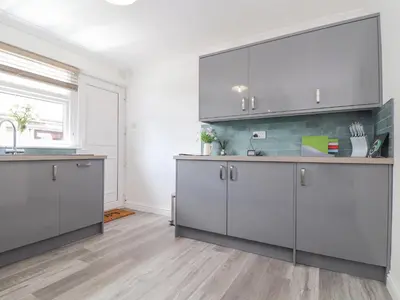 a kitchen with gray cabinets and a sink at Apple Tree Bungalow in Redruth