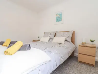 a bedroom with a white bed and a wooden dresser at Apple Tree Bungalow in Redruth