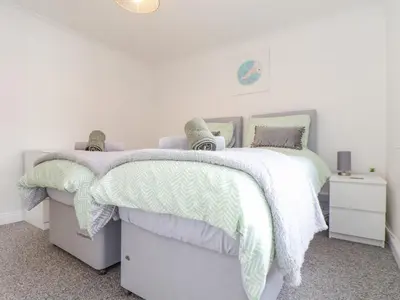 a bedroom with two beds with green and white comforters at Apple Tree Bungalow in Redruth