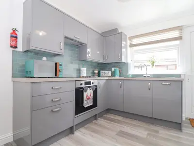 a kitchen with white cabinets and a sink at Apple Tree Bungalow in Redruth