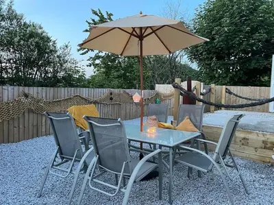 a table and chairs with an umbrella in a backyard at Chy An Lur in Redruth