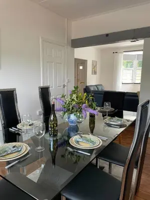 a dining room with a table with glasses and flowers at Chy An Lur in Redruth