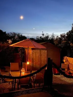 a table with an umbrella and chairs and a shed at Chy An Lur in Redruth