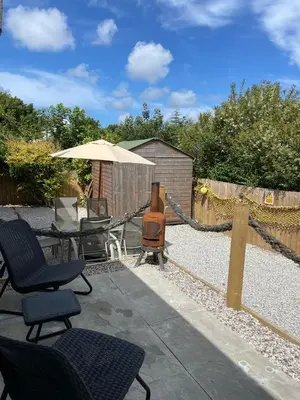 a patio with chairs and an umbrella and a grill at Chy An Lur in Redruth