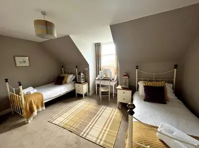 a bedroom with two beds and a desk in it at Riverside Apartment in Uny Lelant