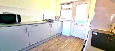 a kitchen with white cabinets and a sink and a window at 8 Penhale in Perranporth
