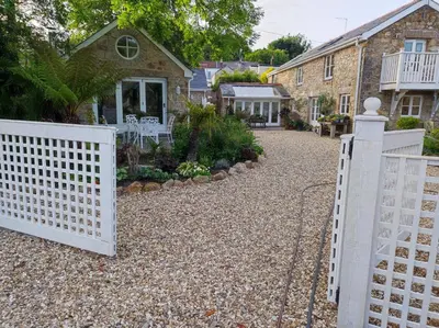 a white fence in front of a house at Tree Fern Barn in St Austell