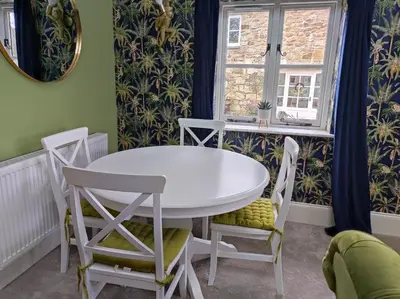 a white table and chairs in a room with a window at Tree Fern Barn in St Austell