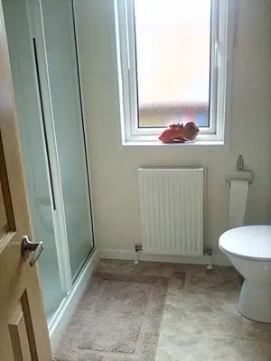 a bathroom with a toilet and a window with a stuffed animal at LakeView Lodge Trevella Park in Crantock