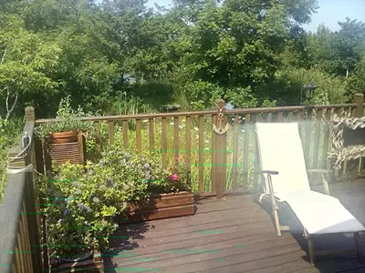 a wooden deck with a bench and some plants at LakeView Lodge Trevella Park in Crantock