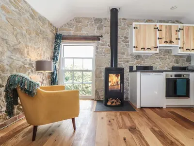 a living room with a stone wall and a fireplace at The Hayloft in Helston