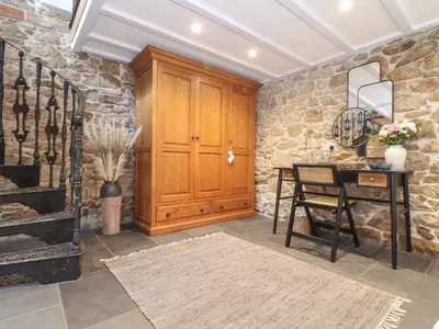 a dining room with a table and a stone wall at The Hayloft in Helston