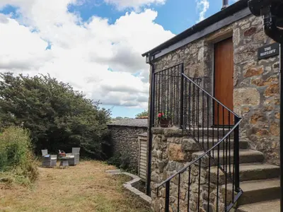 a stone building with a staircase next to a door at The Hayloft in Helston