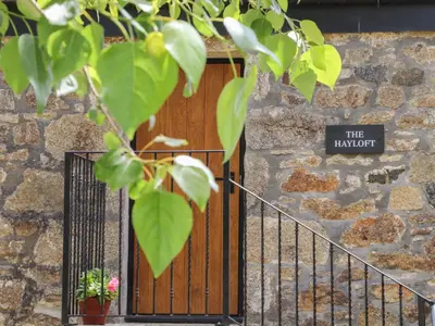 a wooden door with a sign on a stone wall at The Hayloft in Helston