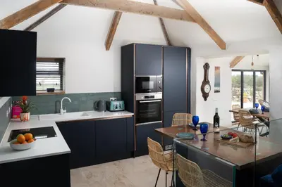 a kitchen with black cabinets and a dining room at The Rum House in Helston