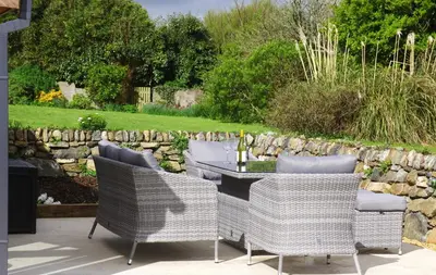 a patio with a table and chairs and a stone wall at The Rum House in Helston