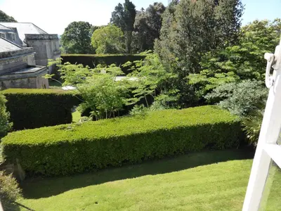 a garden with green hedges and plants at The Old Stables of heritage Tregrehan Garden Cottages on South Coast in St Austell