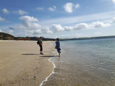 two people standing in the water on a beach at The Old Stables of heritage Tregrehan Garden Cottages on South Coast in St Austell