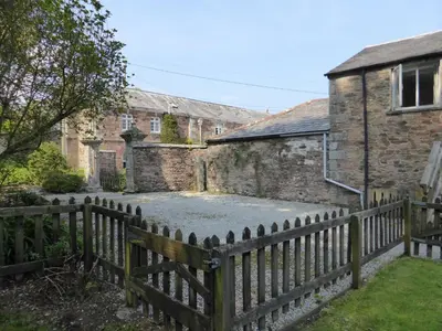 a wooden fence in front of a building at The Old Stables of heritage Tregrehan Garden Cottages on South Coast in St Austell