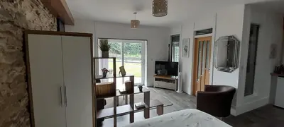 a room with a bed and a living room with a television at Wisteria Barn, Trewethen, Nr Port Isaac in Port Isaac