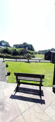 a wooden bench sitting on a sidewalk in a park at Wisteria Barn, Trewethen, Nr Port Isaac in Port Isaac