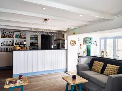 a living room with a couch and a bar at Lugger Hotel ‘A Bespoke Hotel’ in Portloe