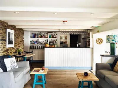 a living room with a couch and a bar at Lugger Hotel ‘A Bespoke Hotel’ in Portloe
