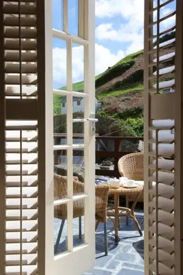 a door leading to a patio with a table and chairs at Lugger Hotel ‘A Bespoke Hotel’ in Portloe