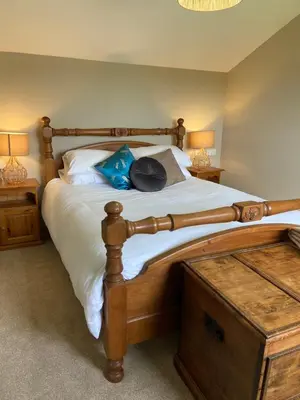 a bedroom with a large wooden bed with two lamps at Moorland Breeze in Blisland