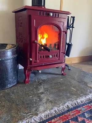 a red wood stove with a fire in it at Moorland Breeze in Blisland