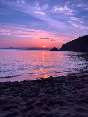 a sunset on a beach with the sun setting over the water at Moorland Breeze in Blisland