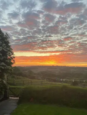 a sunset on a hill with a fence and a field at Moorland Breeze in Blisland