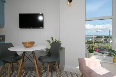 a living room with a table and chairs and a tv at SeaBreeze 3 - seaview & Parking in St Ives