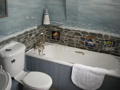a bathroom with a toilet and a bath tub with a sink at Church Cottage in Bude