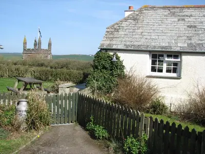 a white house with a fence in front of it at Church Cottage in Bude