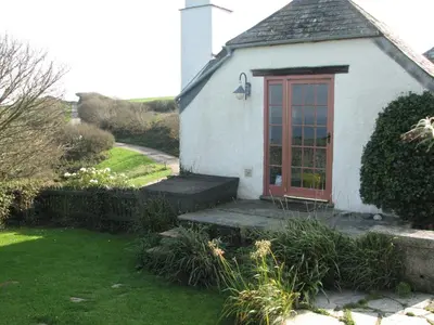 a small white house with a red door at Church Cottage in Bude