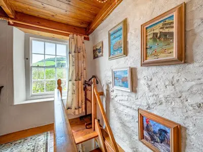 a staircase in a house with paintings on the wall at Holiday Home The Homestead by Interhome in Gorran Haven